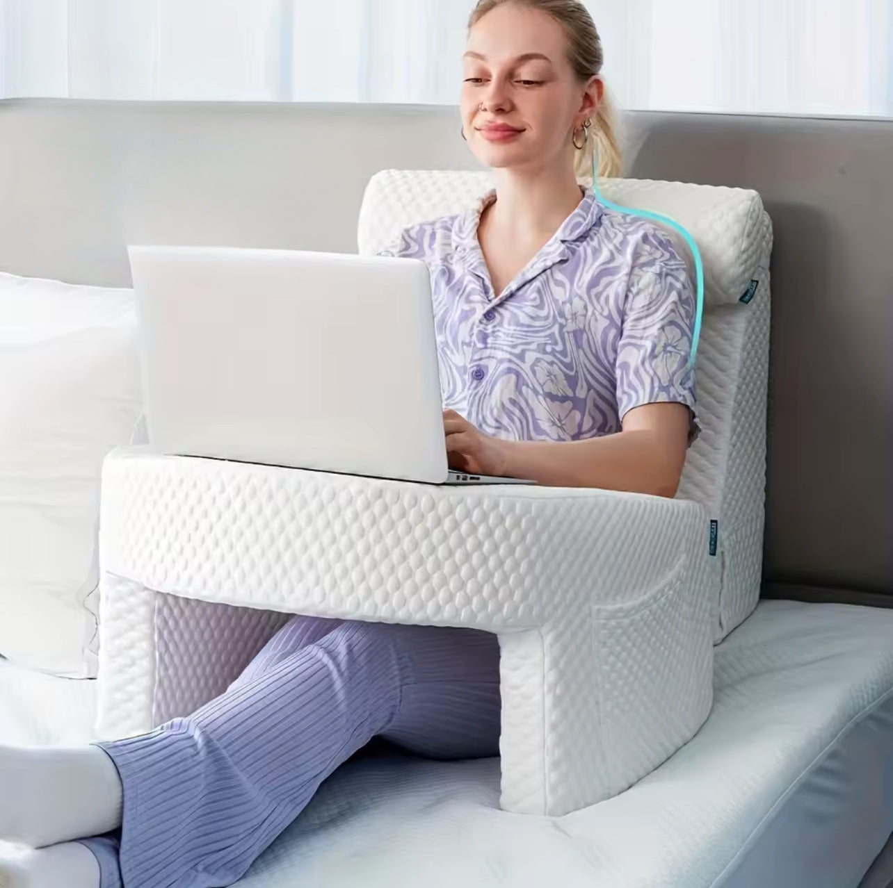 Woman using a laptop on a portable desk pad while sitting in bed, showcasing comfort and ergonomic design.