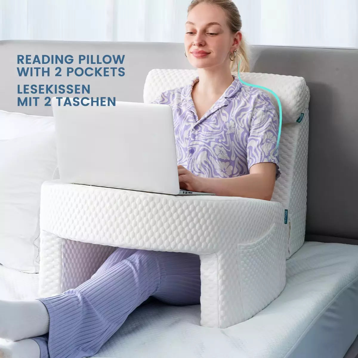 Woman using a reading pillow with two pockets for comfort while working on a laptop, sitting on a bed.